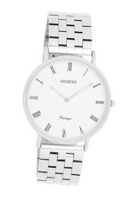 Montre en acier inoxydable argenté avec un cadran rond blanc, des chiffres romains noirs et un bracelet en maille avec des maillons rectangulaires.