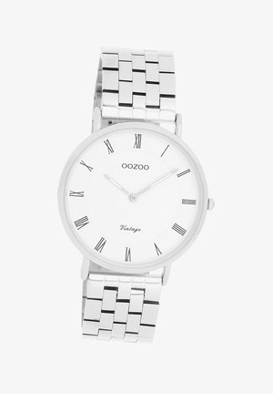 Montre en acier inoxydable argenté avec un cadran rond blanc, des chiffres romains noirs et un bracelet en maille avec des maillons rectangulaires.