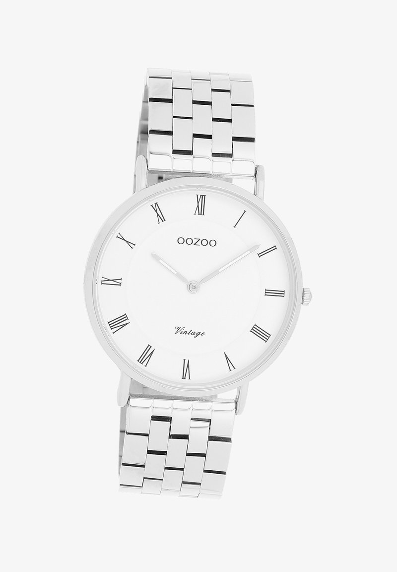 Montre en acier inoxydable argenté avec un cadran rond blanc, des chiffres romains noirs et un bracelet en maille avec des maillons rectangulaires.