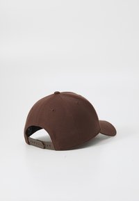 Brun kasket lavet af stof, med en buet skygge, justerbar rem bagpå og ventilationshuller på siderne.
