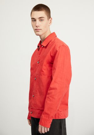 Red, button-up jacket with a collar, two front pockets, and a relaxed fit. Made from a smooth fabric with a slightly faded texture.