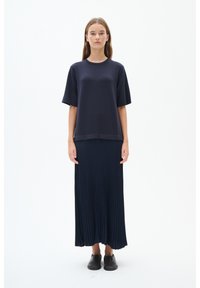 Niebieski t-shirt z krótkim rękawem nałożony na długą do kostek plisowaną spódnicę w tym samym kolorze. Strój charakteryzuje się prostą i gładką fakturą, dopełniony butami na wsuwkę.