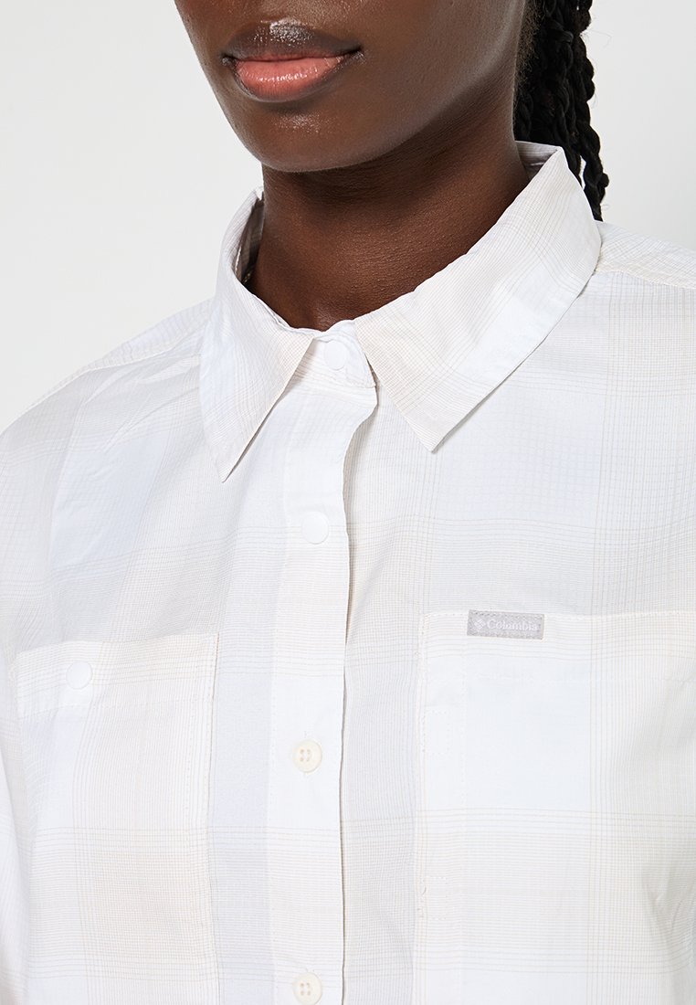 Koszula z krótkim rękawem, z kołnierzykiem w kolorze białym, z delikatnym wzorem w kratkę. Posiada podwójne kieszenie na piersi zapinane na guziki oraz metkę z logo na lewej kieszeni.