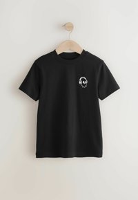 T-shirt nera in cotone, con maniche corte e scollo rotondo. Un design di teschio bianco con cuffie è stampato sulla parte sinistra del petto.