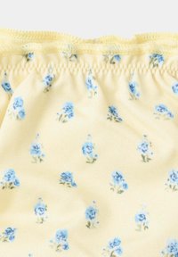 Tissu jaune avec bord froncé et petit motif floral de roses bleues dispersé uniformément sur la surface.