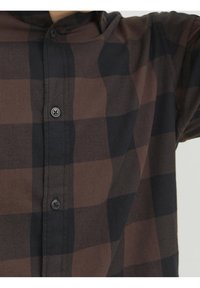 Camicia a quadri marrone e nera con bottoni. Realizzata in un tessuto dal morbido tocco. Presenta un colletto standard e bottoni neri.