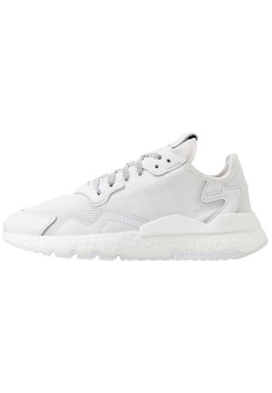 Biały sportowy sneaker z teksturowaną podeszwą, siateczkową i syntetyczną cholewką, wzorzystymi sznurowadłami i wyściełanym kołnierzem, pokazany z profilu.