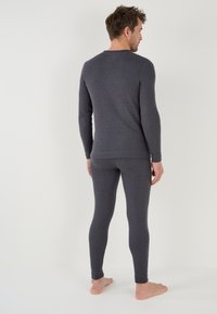 Camiseta térmica gris de manga larga y leggings. Diseño suave y ajustado con puños acanalados y cuello redondo. Adecuado para usar en capas.