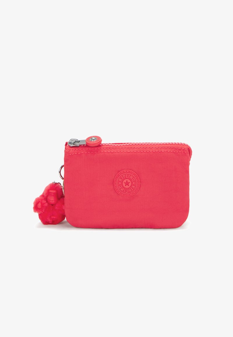 Small pink fabric wallet with a zipper closure, logo embossed on the front, and a fluffy monkey keychain attached.