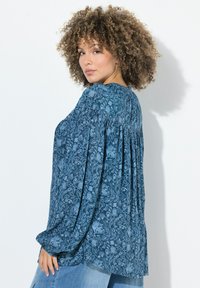 Blusa a maniche lunghe con motivo floreale blu, design con schiena plissettata, realizzata in tessuto leggero, dotata di scollatura tonda e vestibilità rilassata.