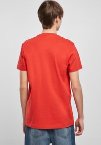 Rode katoenen t-shirt met korte mouwen en een ronde hals. Glad textuur en relaxed fit. Achteraanzijde toont geen zichtbare patronen of logo's.