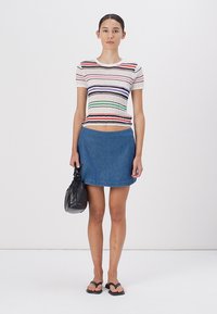 Stripet strikket topp med flere farger; denim mini skjørt; svart håndveske; svarte flip-flops; glatte teksturer; tettsittende design.