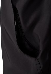 Gros plan sur un tissu noir montrant une poche zippée partiellement ouverte avec des coutures visibles.