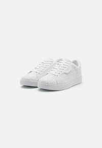 Baskets blanches avec un motif texturé, présentant un design à lacets et une semelle rembourrée. Surface lisse et accents discrets.