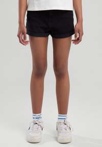 Denim shorts in dark blue with rolled cuffs, paired with white sneakers and blue-striped socks. Simple design, casual fit, and clean lines.