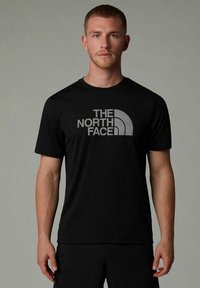 Camiseta negra de manga corta con un logo gris "THE NORTH FACE" en el pecho. Fabricada con un material suave, presenta un ajuste clásico.