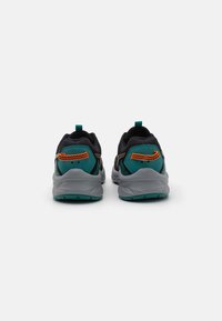 Baskets de sport noires avec des accents teal et des détails orange, présentant une tige en maille texturée, une semelle rembourrée et des languettes au talon.