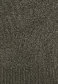 Ciemnozielona dzianina z teksturową powierzchnią i prążkowanym brzegiem na dole. Całościowy wygląd jest jednorodny i ciasno tkany.