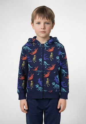 Capuchonvest met ritssluiting gemaakt van zachte stof, met een marineblauwe achtergrond en kleurrijke dinosaurusprints in rood, blauw, groen en geel.