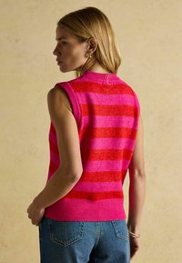 Ärmelloser Pullover mit pinken und roten horizontalen Streifen, strukturiertem Strick, geripptem Saum und runden Halsausschnitt, kombiniert mit blauen Jeans.