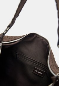 Braune gewebte Stofftasche mit einem Reißverschluss, glatter Fütterung und einer zusätzlichen Reißverschlusstasche. Verfügt über ein Pull&Bear-Label.