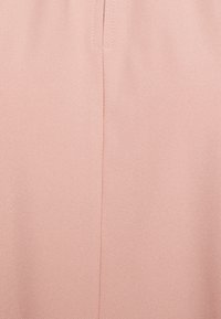 Světle růžová tkanina s texturovaným povrchem, s vertikálním švem uprostřed. Materiál je hladký a lehký.