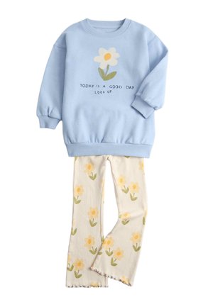 Lyseblå sweatshirt med en hvid blomst og teksten "Today is a good day look up", kombineret med cremefarvede bukser med gule blomsterprint.