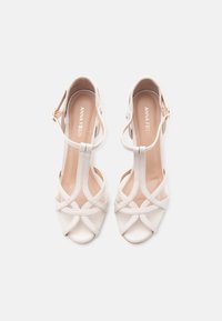 Ζευγάρι κομψών μπεζ σανδαλιών με ψηλό τακούνι, σχεδιασμό T-λαιμού και αγκράφα στον αστράγαλο, επωνυμίας "Anna Field", φωτογραφημένα από πάνω σε λευκό φόντο.