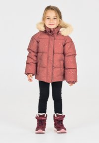 Polstret bordeaux jakke med hvide sprøjt, parret med sorte leggings og bordeaux støvler med lyserøde accenter.