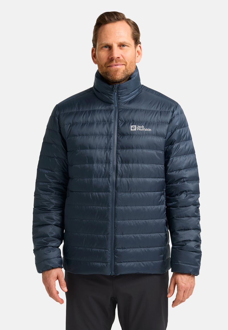 Veste matelassée bleu marine avec un col haut, comportant une fermeture éclair à l'avant et des détails cousus. Logo sur la partie supérieure gauche de la poitrine.