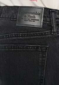 Μαύρο τζιν από denim με δερμάτινο έμπλαστρο που φέρει ανάγλυφο λογότυπο, λεπτομερείς ραφές και κλασικό σχέδιο με πέντε τσέπες.