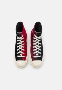Sneaker alta con tomaia in velluto nero e bordeaux, lacci bianchi e suola in gomma beige con punta lucida.