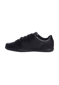 Zapatilla negra hecha de cuero liso con un panel lateral texturizado, punta redonda y cordones planos. Presenta un logo sutil en el lateral.