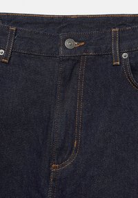 Temno modre kavbojke iz jeansa z vidnim šivom, kovinsko gumbo in petžepno zasnovo. Teksturirana tkanina z gladko površino.