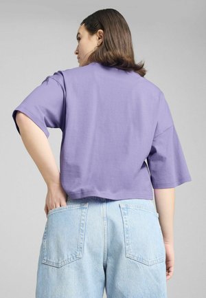 T-shirt viola cropped e dal taglio morbido, realizzata in cotone morbido. Presenta maniche corte e orlo dritto, abbinata a pantaloni shorts in denim azzurro.