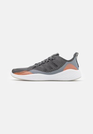 Baskets de sport grises et orange avec semelle blanche, tige en mesh, design à lacets et languette au talon, vues de profil droit.