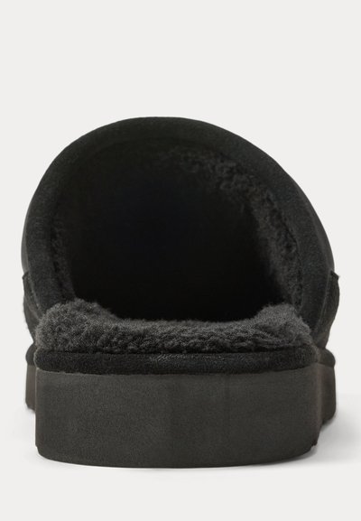 Black slipper with plush, fuzzy lining and thick sole, shown from the back on a plain white background.