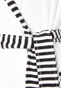 White robe detail featuring a black and white striped tie, made of soft fabric with a textured finish. The tie is securely knotted at the waist.