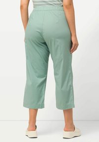 Ljust gröna, capribyxor gjorda av mjukt tyg. Har resårmidja och en lös passform, som slutar strax ovanför anklarna.