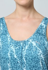 Débardeur bleu clair avec un motif géométrique composé de formes triangulaires, un col rond plongeant et un détail froncé au niveau de la poitrine.