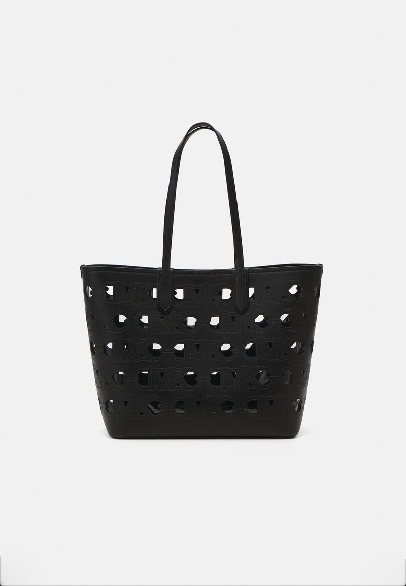 Sac cabas noir avec motif répétitif découpé du logo "MK" et deux longues anses, présenté sur un fond blanc uni.