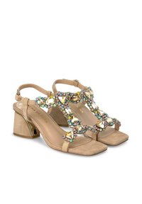 Sandalias de tacón bloque de ante beige con una correa decorativa adornada con gemas multicolores. Diseño de punta cuadrada y cierre de hebilla en el tobillo.