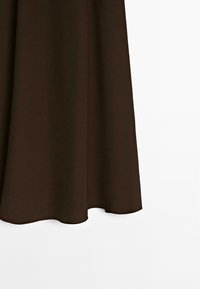 Jupe en tissu marron avec une texture lisse, de forme A-line et un ourlet courbé. Design simple sans décorations ni motifs.