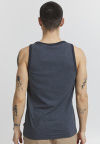 Dunkelblaues Tanktop mit Rundhalsausschnitt und kontrastierenden dunklen Besätzen. Hat eine weiche Textur und eine figurbetonte Passform, die Tattoos an den Armen zur Geltung bringt.