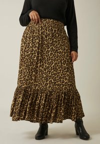 Falda larga de estampado de leopardo en tonos marrón y negro, con un dobladillo rizado y una cinturilla ancha, combinada con botas negras hasta el tobillo.