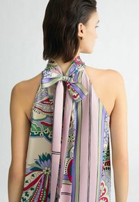 Bezramkowy top na halter w lekkim, wzorzystym materiale z różowymi, zielonymi i fioletowymi kolorami, z kokardką przy szyi.