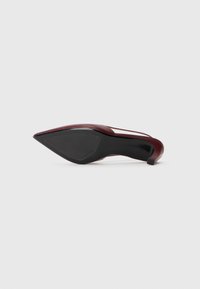 Pump bordeaux con tacco alto, dalla punta appuntita e design elegante, con suola in gomma nera e un sottile dettaglio intagliato sui lati.