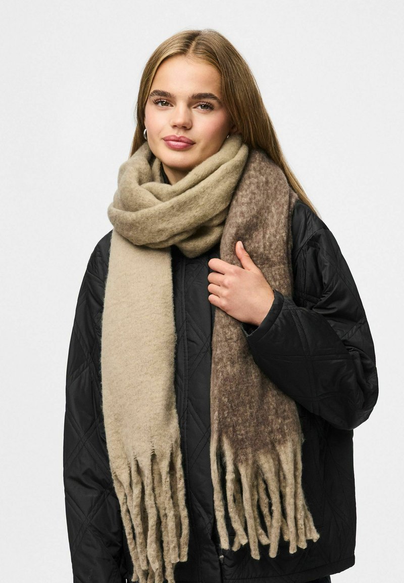 Uldblandede tørklæde med en beige og brun gradient, med frynset kanter og en blød tekstur, draperet om halsen.