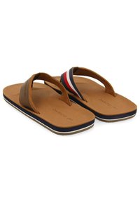 Chanclas marrones con una correa texturizada en marrón y un acento a rayas en azul marino, rojo y blanco. Suela acolchada con plantilla de goma.