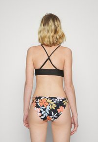 Top de bikini preto com alças entrelaçadas; parte de baixo com padrão floral apresentando flores em laranja, vermelho e azul sobre um fundo escuro.
